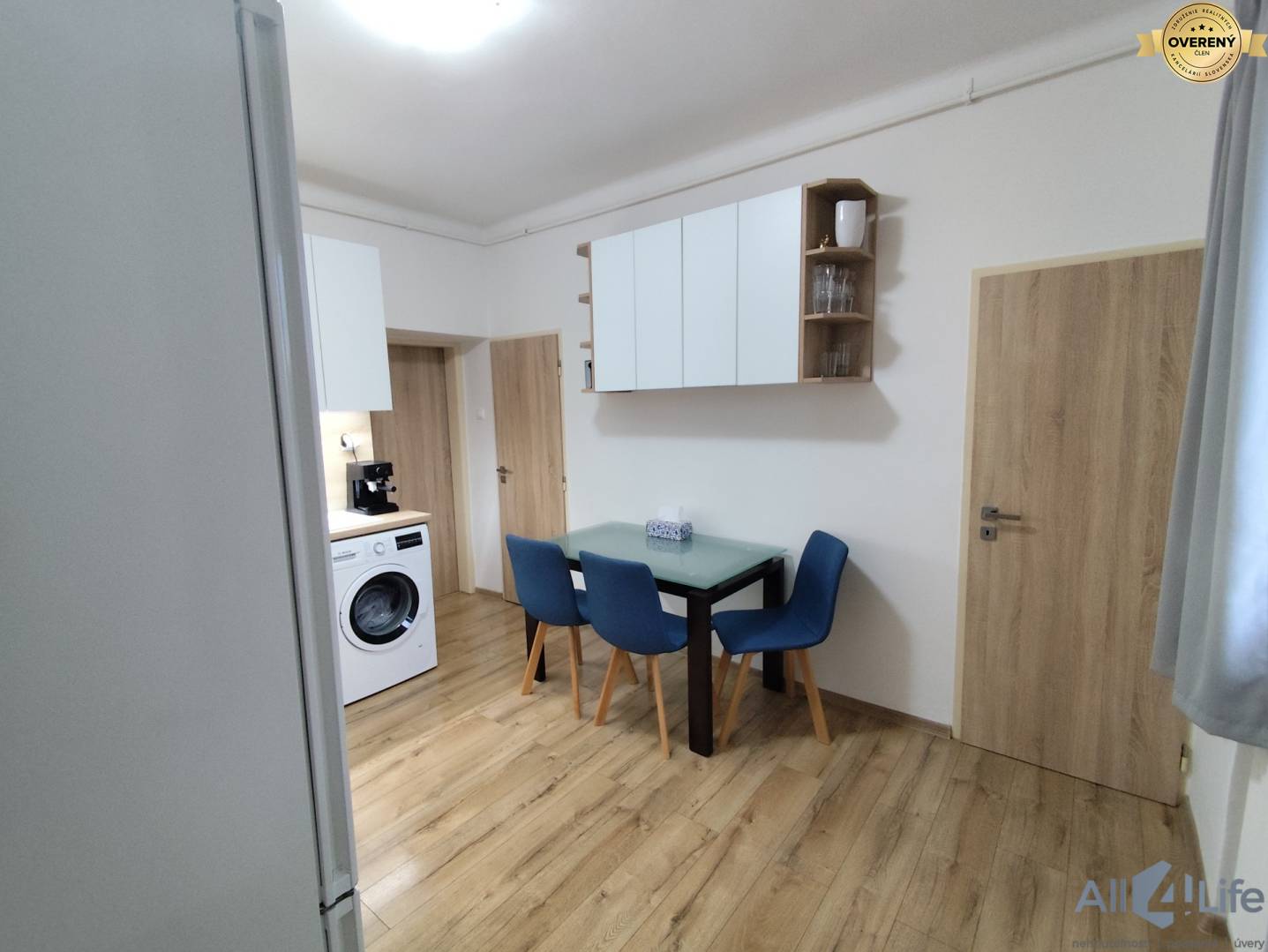 Kuchynka v rodinnom dome s práčkou a podlahou s dreveným dekorom.