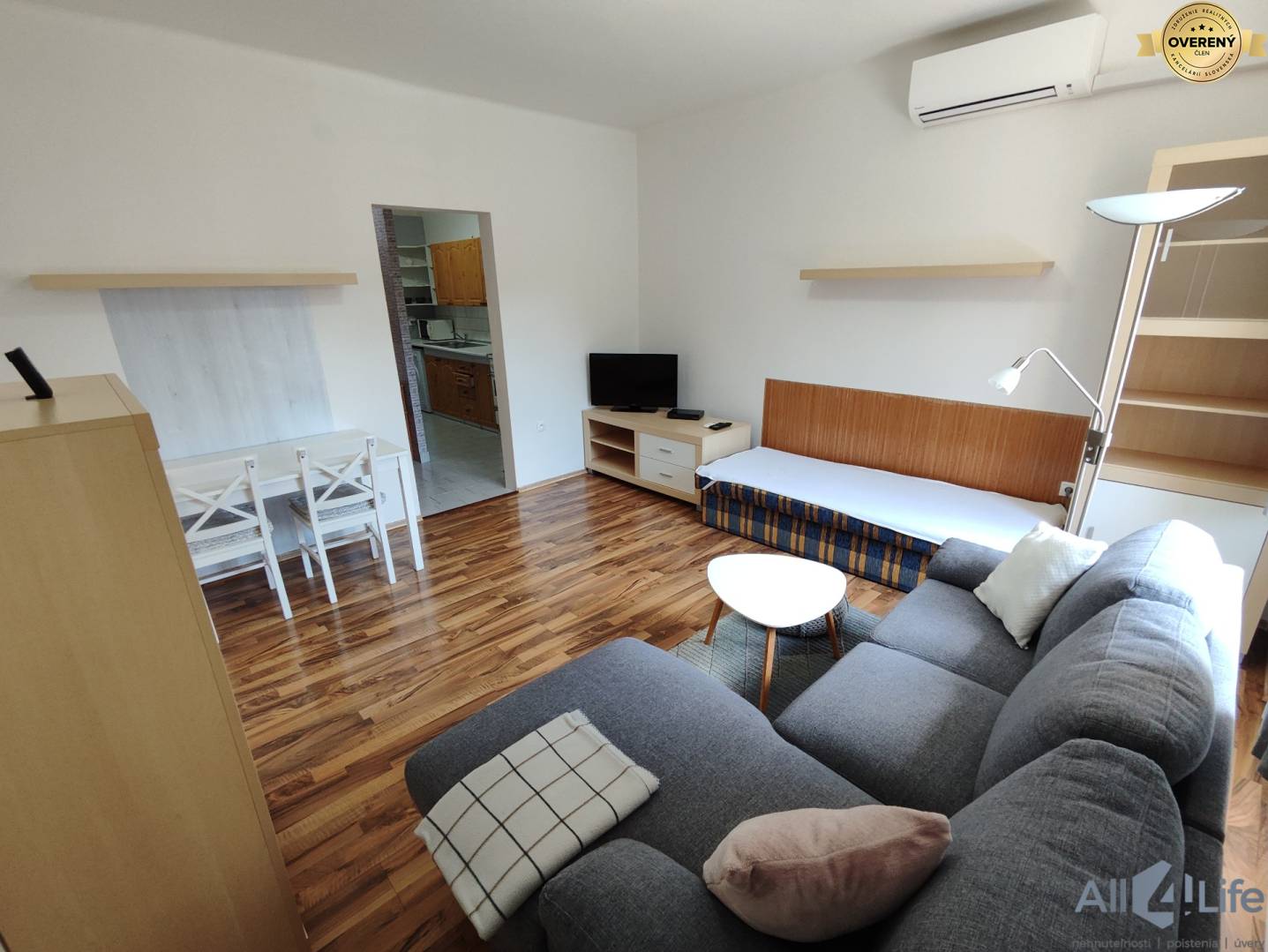 Obývacia izba v rodinnom dome s podlahou s dreveným dekorom, sedačkou a jedálenským kútom.