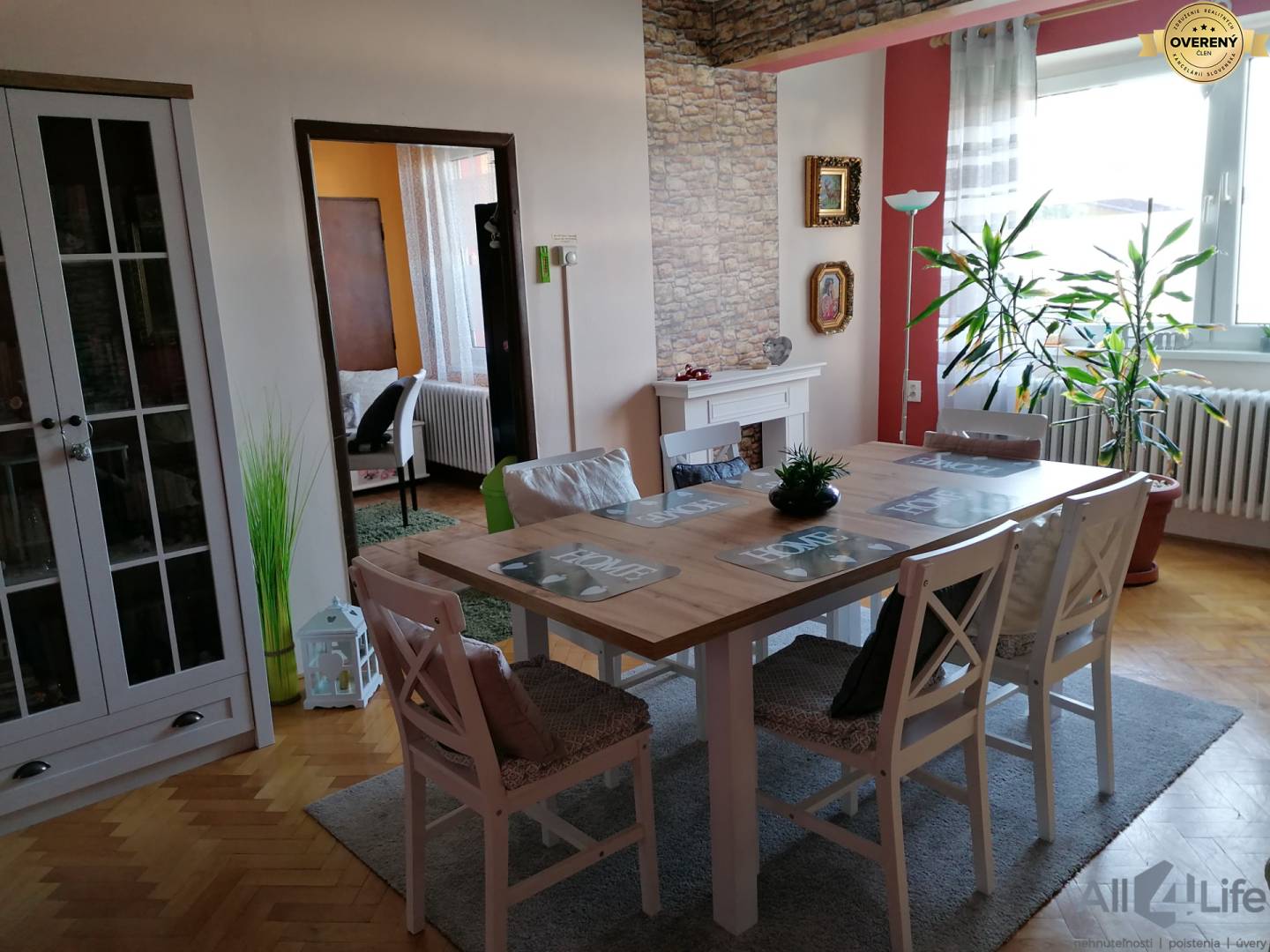 Jedáleň v rodinnom dome so stolom, stoličkami, kvetmi a podlahou s dreveným dekorom.