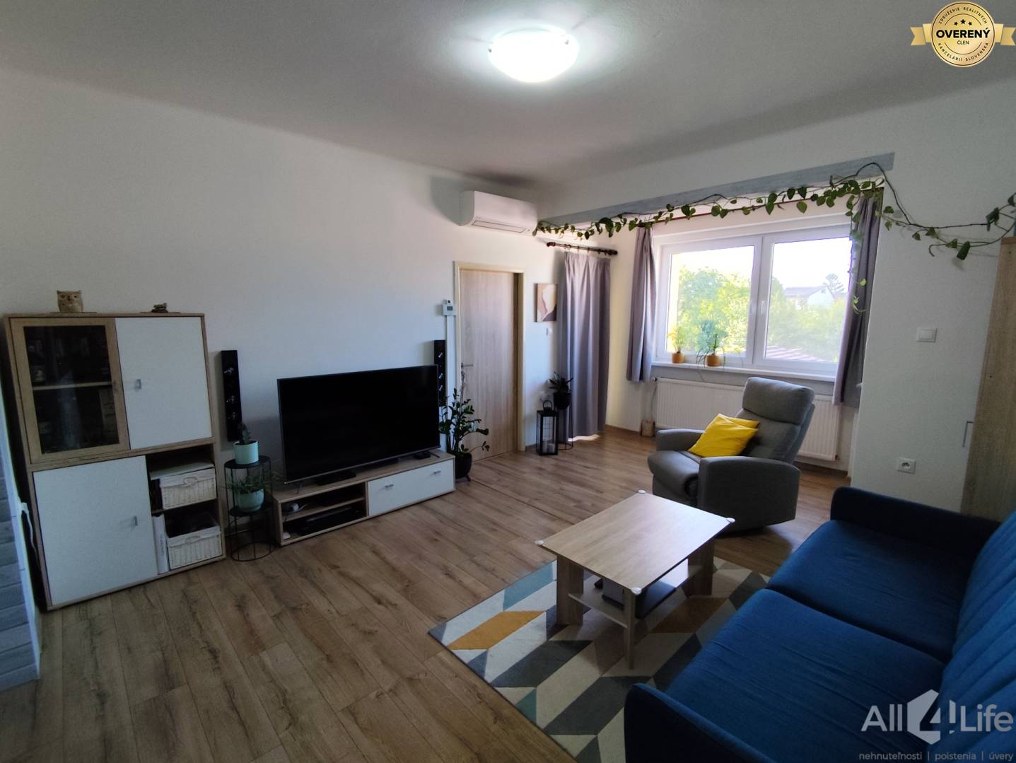 Obývacia izba v rodinnom dome s podlahou s dreveným dekorom a pohodlným sedením.