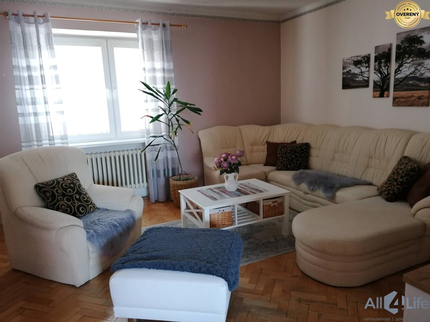 Obývačka v rodinnom dome s béžovou sedačkou, rastlinou a podlahou s dreveným dekorom.