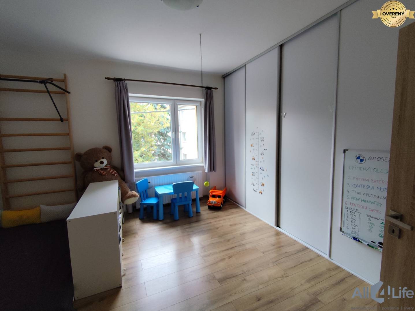 Detská izba v rodinnom dome s podlahou s dreveným dekorom, hračkami a nábytkom.