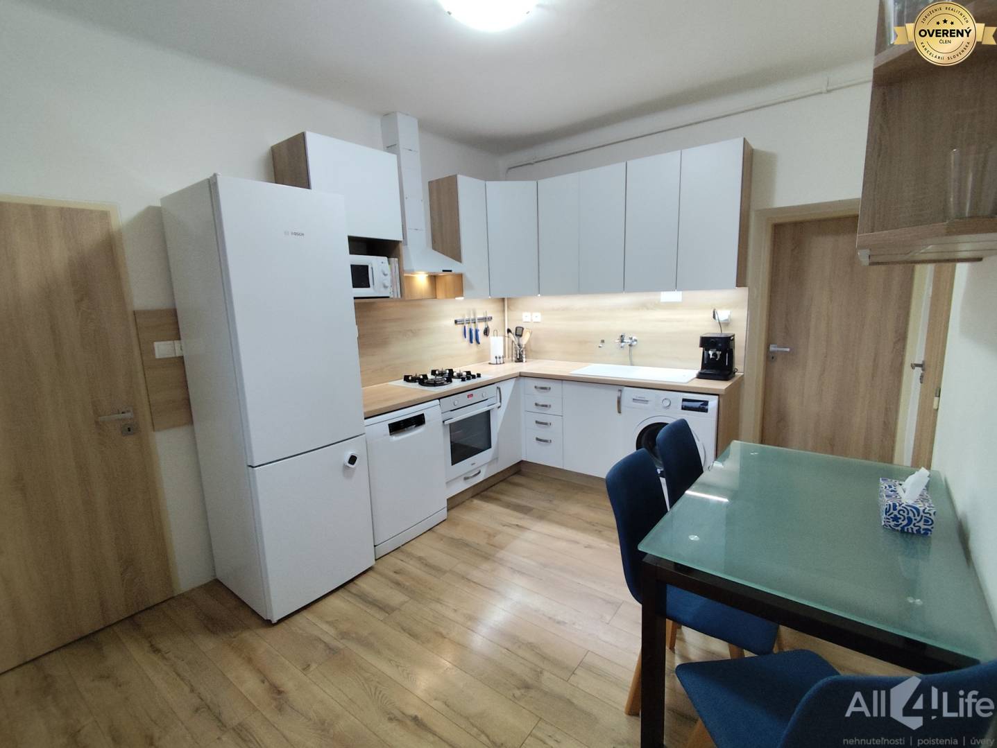 Kuchyňa v rodinnom dome s podlahou s dreveným dekorom a bielymi spotrebičmi.