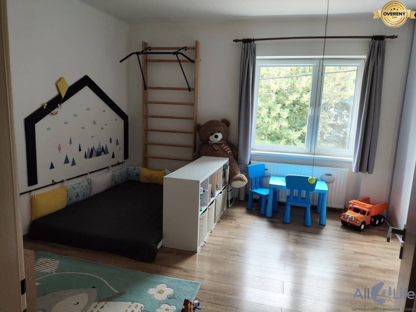 Detská izba v rodinnom dome s podlahou s dreveným dekorom, nábytkom a hračkami.
