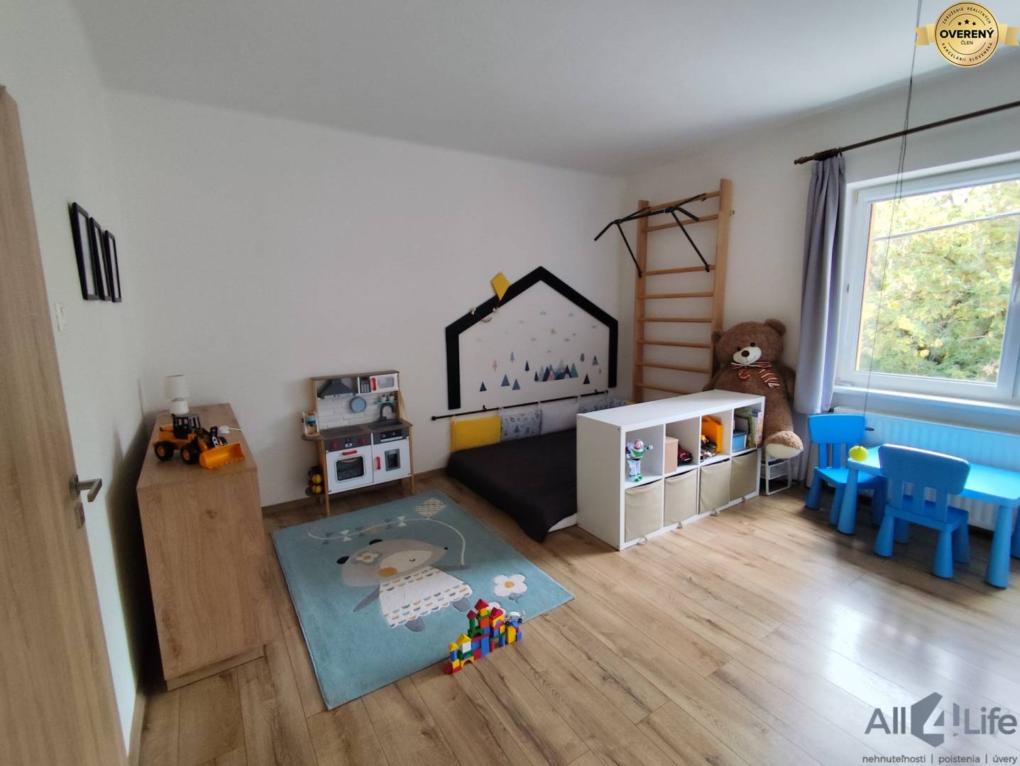Detská izba v rodinnom dome s podlahou s dreveným dekorom a hračkami.