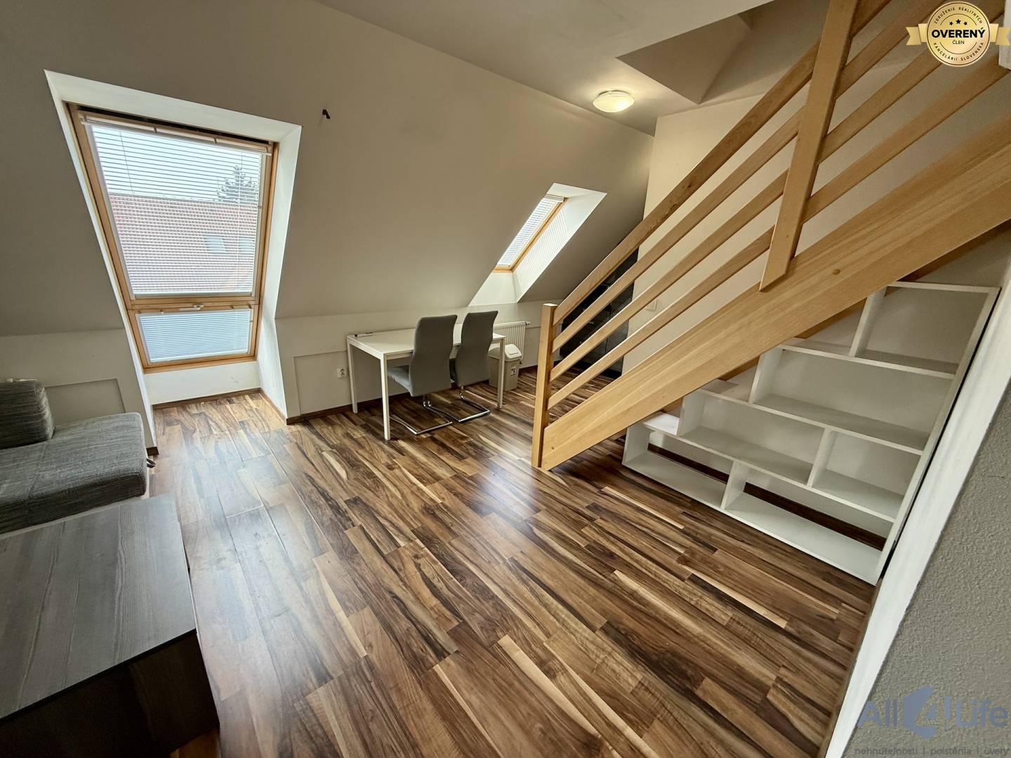 Podlaha s dreveným dekorom, schodisko, písací stôl a kreslá v 2-izbovom byte.