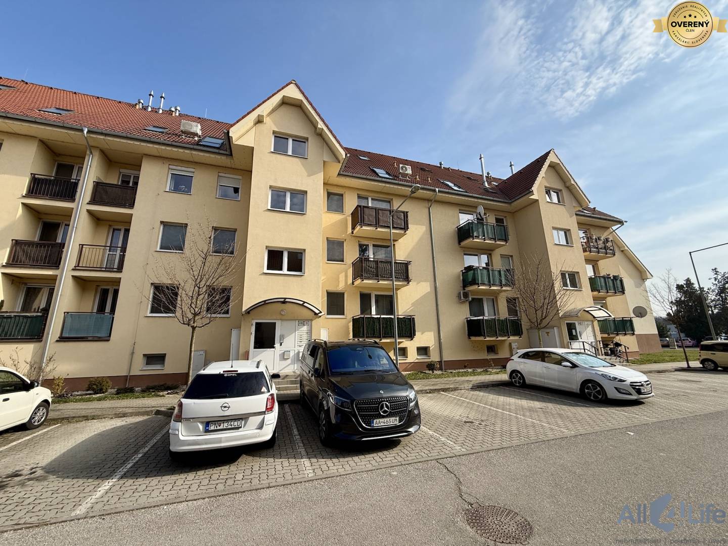 Bytový dom na Čachtickej ulici v Piešťanoch s parkoviskom a autami.