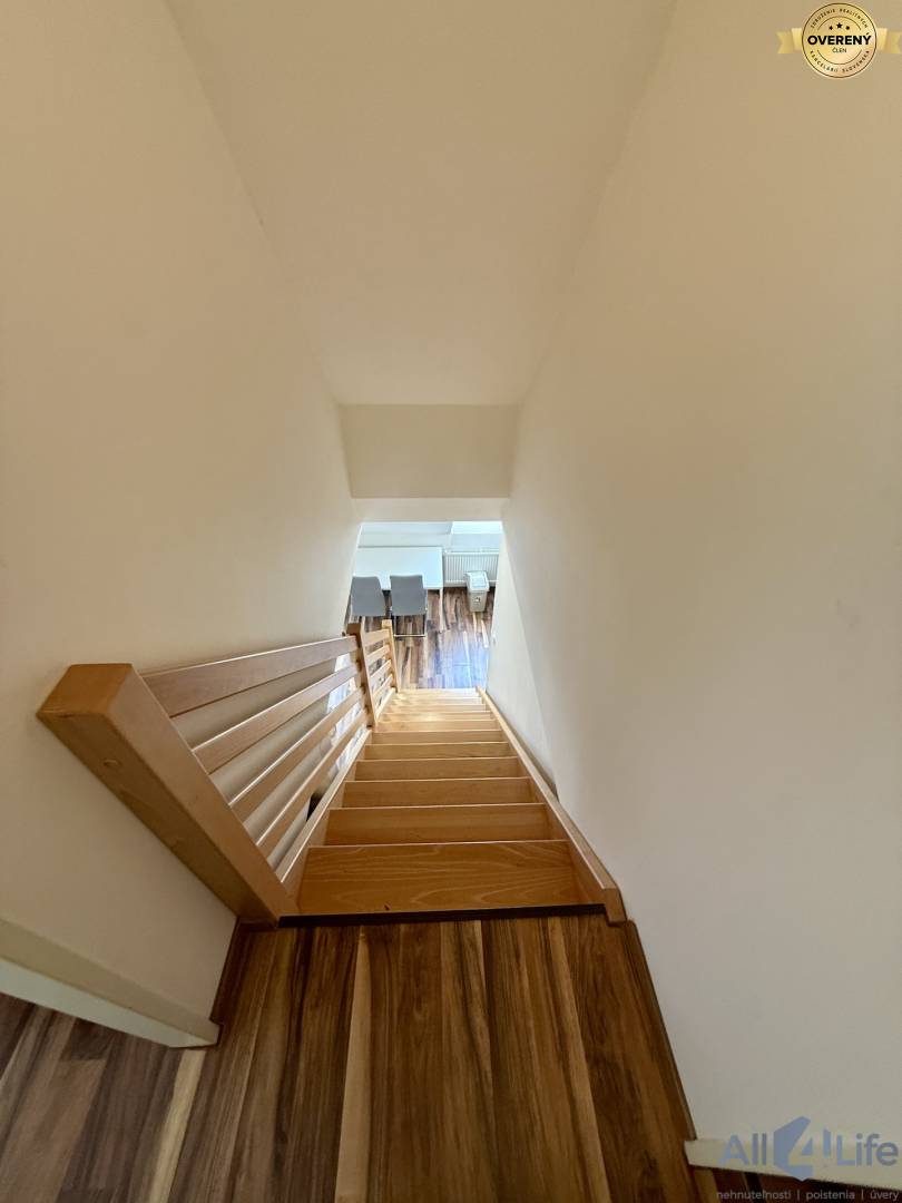 Drevené schodisko so zábradlím a podlahou s dreveným dekorom v 2-izbovom byte.