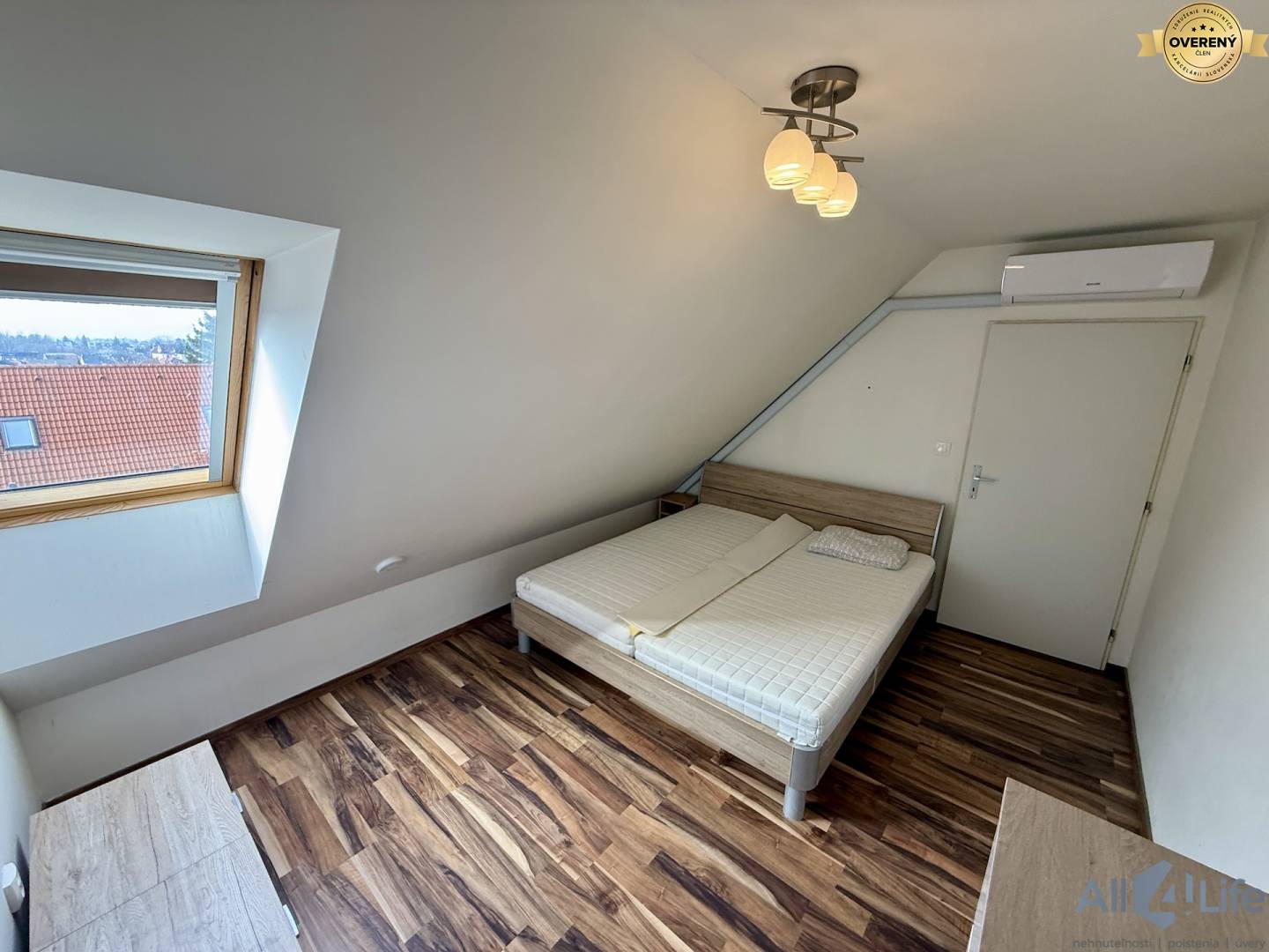 Spálňa v 2-izbovom byte s podlahou s dreveným dekorom a strešným oknom.