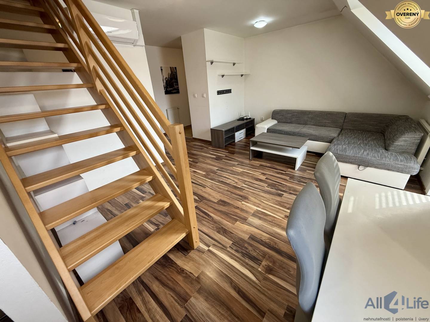 Dvojposchodový obývací priestor s podlahou s dreveným dekorom a pohodlnou sedacou súpravou.