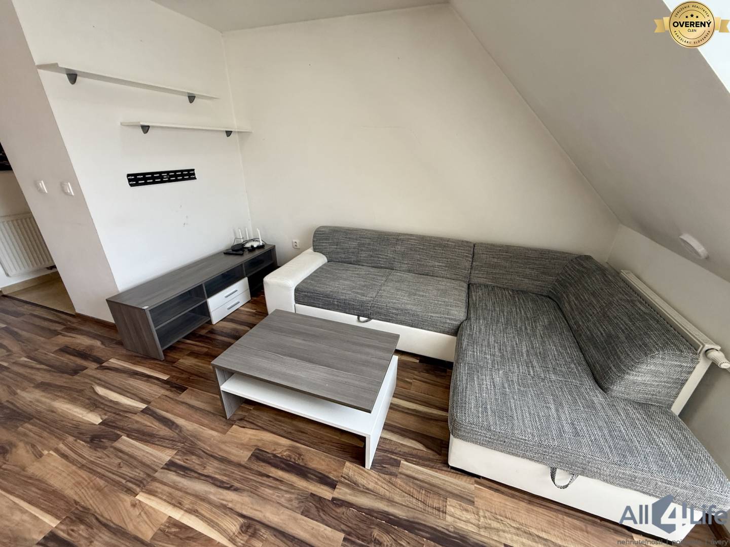 Obývacia izba s pohovkou, konferenčným stolíkom a podlahou s dreveným dekorom v 2-izbovom byte.