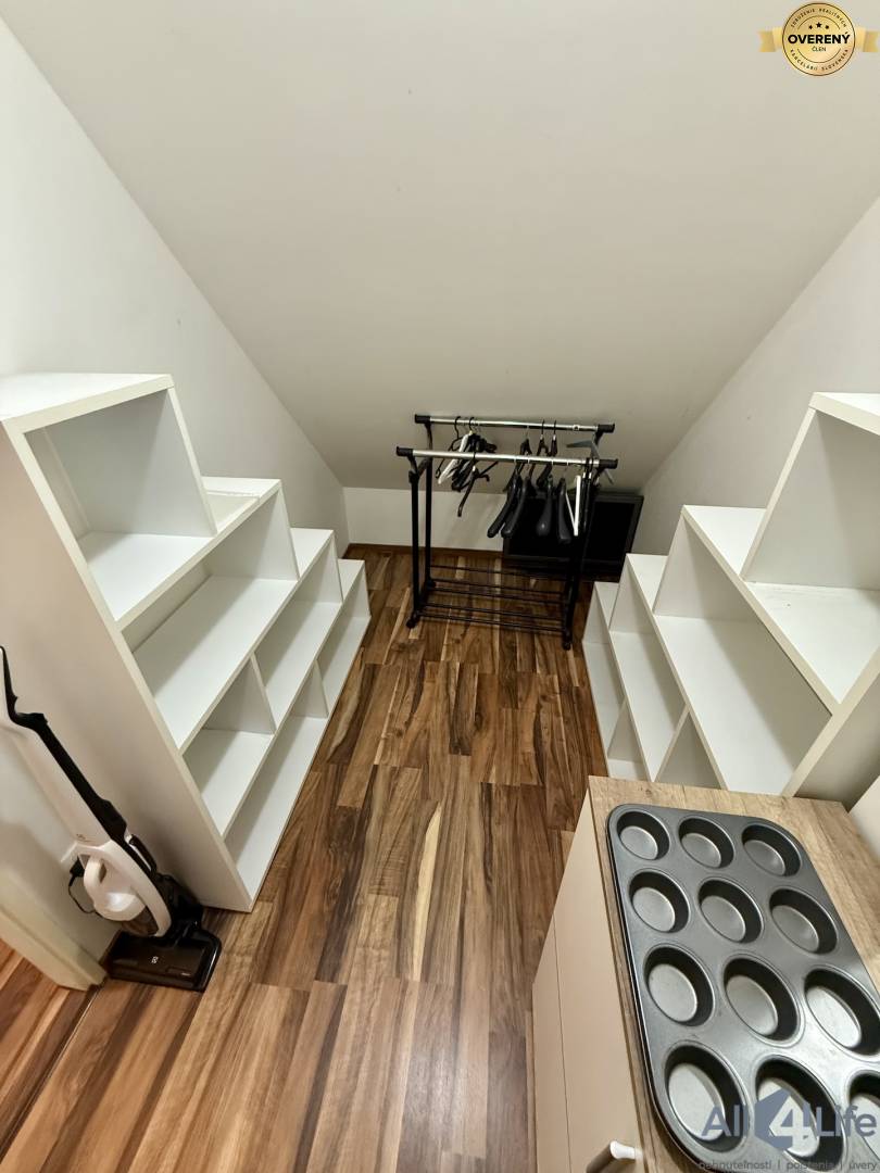 Šatník v 2-izbovom byte s policami, vešiakmi a podlahou s dreveným dekorom.