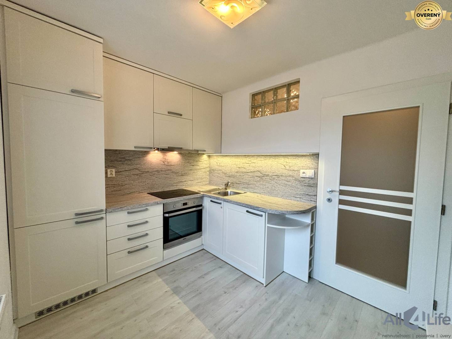 Kuchyňa v 1-izbovom byte s modernou linkou a podlahou s dreveným dekorom.