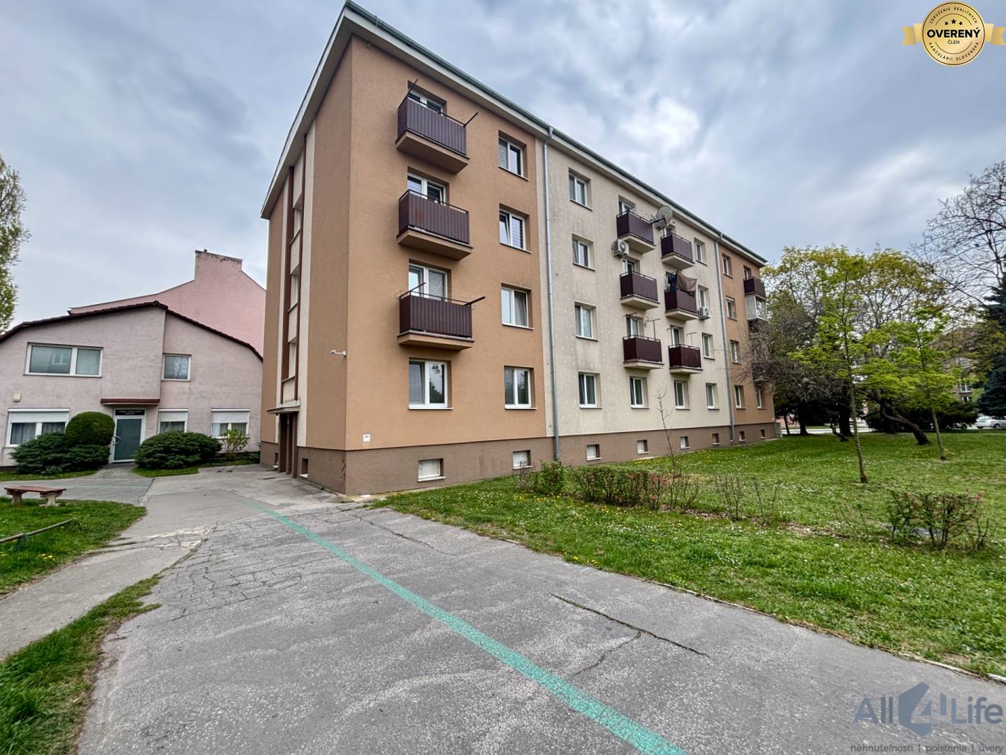 Štvorposchodový bytový dom na Krajinskej ceste v Piešťanoch obklopený zeleňou.