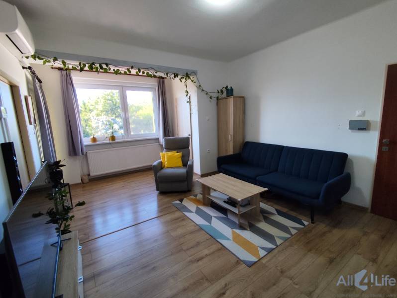 Obývacia izba rodinného domu s pohodlným sedením a podlahou s dreveným dekorom.