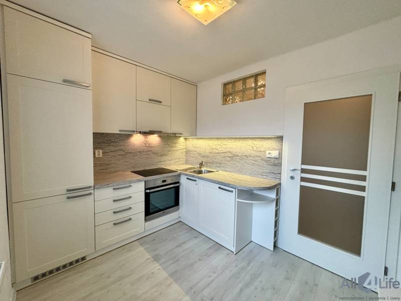 Kuchyňa v 1-izbovom byte s modernou linkou a podlahou s dreveným dekorom.